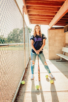 a girl is posing with her baseball bat