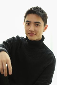 a young man in a black turtle neck sweater pointing at the camera with his right hand