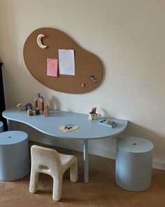 a child's table and stools in a room with a wall hanging on the wall