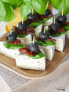 small appetizers with olives and cheese are displayed on a wooden platter