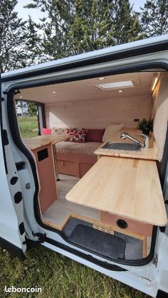 an open van door with a table and sink in the back ground next to some trees