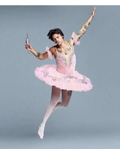 a ballerina in pink is holding a cell phone and posing with her arms outstretched