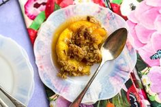 a white plate topped with food on top of a floral table cloth next to silverware