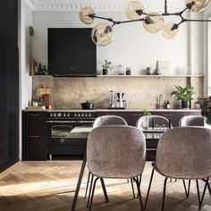 two chairs are sitting in front of a table with four lights hanging from the ceiling