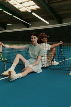 a woman sitting on the ground holding a tennis racquet