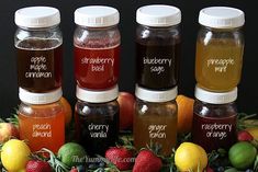 four jars filled with different types of liquid sitting on top of a pile of fruit