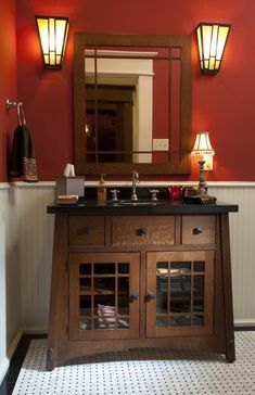 a bathroom with red walls and white tile flooring has a wooden cabinet, mirror, and two lights on the wall