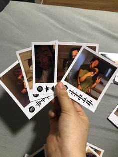 a person holding up four polaroid pictures with the same image on them, in front of a bed