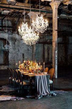 a dining room table is set with candles and flowers in the center, surrounded by chandeliers