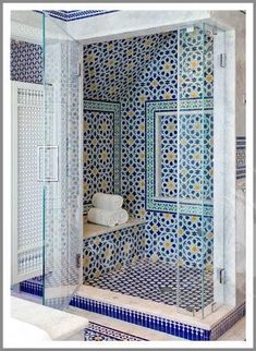 a bathroom with blue and white tiles on the walls, shower stall and countertop