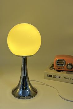 a lamp that is sitting on top of a table next to a book and a radio