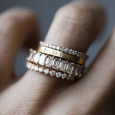 a woman's hand holding a gold ring with three rows of diamonds on it