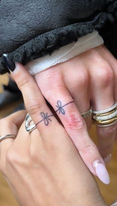 two people with matching rings on their fingers, one has a cross tattoo on it