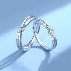 two wedding rings with diamond accents on each one, set against a light blue background