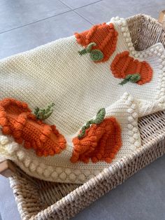 a crocheted blanket with pumpkins on it sitting in a wicker basket