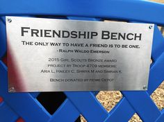 a metal sign on a blue fence that reads, friendship bench the only way to have a friend is to be one