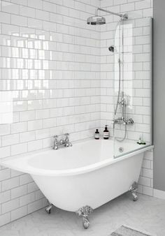 a white bath tub sitting next to a toilet in a bathroom under a window with potted plants