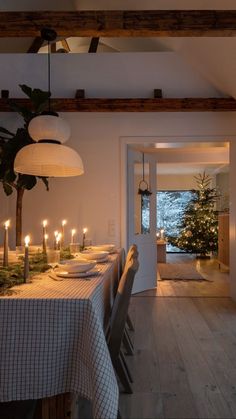 a dining room with candles on the table and christmas tree in the corner behind it