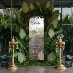 a sign that says bride and groom on it next to two candles with greenery