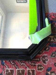 a mirror with some tape on it and a green piece of paper taped to the frame