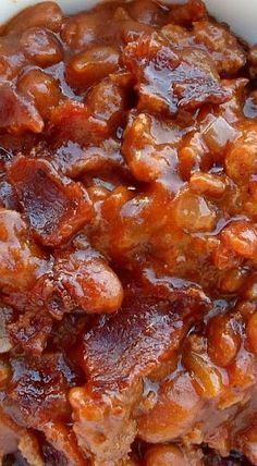 a white bowl filled with meat covered in bbq sauce on top of a wooden table