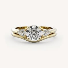 a yellow gold engagement ring with two diamonds on the band and a round diamond in the center