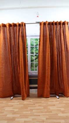 an orange curtain is open in front of a window with wood floors and windowsills