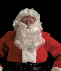 a man dressed as santa claus standing in front of a black background