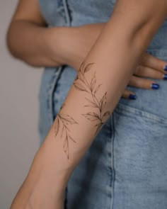 a woman's arm with a tattoo on it that has flowers and leaves growing out of it