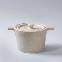 a white ceramic pot with a lid on a gray background, it looks like something out of space