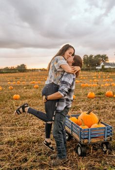 a man and woman hugging in a field with pumpkins