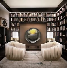 two white chairs sitting in front of a book shelf filled with books