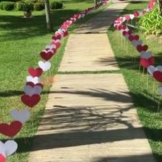 some red and white hearts are lined up on the side of a sidewalk in front of a house