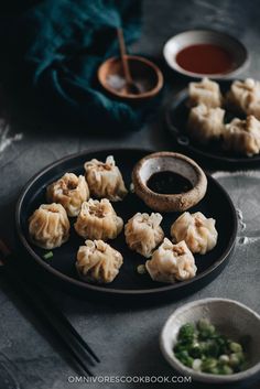 dumplings on a plate with dipping sauce and chopsticks