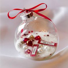 a glass ornament filled with snow and red ribbon