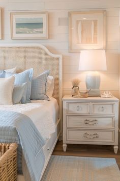 a white bed sitting in a bedroom next to a night stand with two lamps on top of it