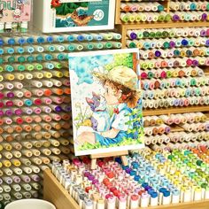 there are many different colored crayons on the shelf and one is holding a painting