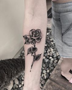 a black and white rose tattoo on the left arm by a woman's foot