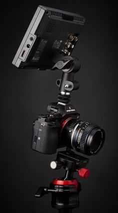 a camera attached to a tripod on a black background with the lens pointed up