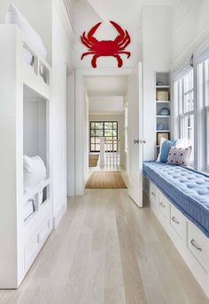 a room with white walls and wooden floors has a blue bench in front of the window