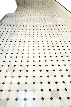 a white and black tiled floor with an escalator in the middle on it