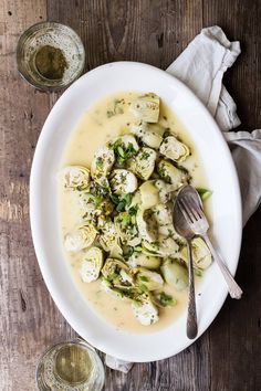 a white bowl filled with potatoes and broccoli on top of a wooden table