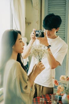 a man taking a picture of a woman holding flowers