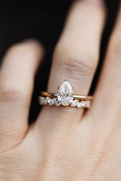 a woman's hand with a diamond ring on top of her finger and an engagement band