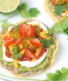 small tortilla topped with avocado, tomatoes and cheese