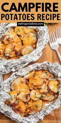 two foil pans filled with baked potatoes on top of a wooden table next to a fork and knife