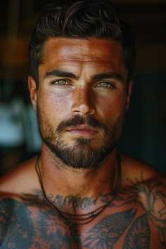 a close up of a man with tattoos on his chest and chest, looking at the camera