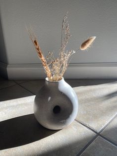 a vase with dried plants in it sitting on the floor