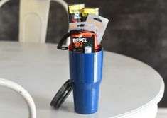 a blue cup sitting on top of a white table next to a plastic container filled with items