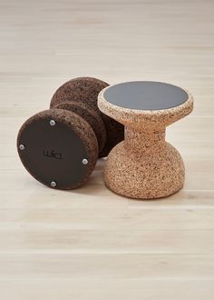 three cork stools sitting next to each other on a wooden floor, one with a black top